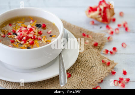 Noahs Pudding in weiße Schüssel. Die getrockneten Früchte, Hülsenfrüchte und Getreide sind mit Weizen und Zucker hergestellt. Es ist mit Nussbaumholz eingerichtet, getrocknete Früchte und pomegr Stockfoto