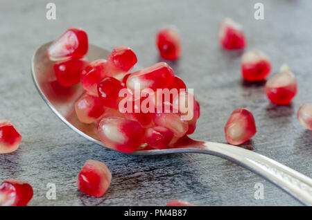 Granatapfel Samen werden in Löffel auf Holztisch. Nahaufnahme, Detail. Stockfoto