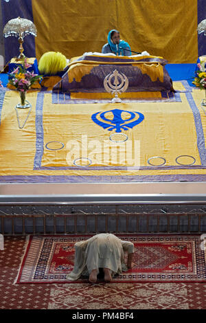 Eine anonyme Frau worshipper Bögen im Gebet am Altar an Baba Makhan Shah Lobana Tempel in Queens, New York. Stockfoto