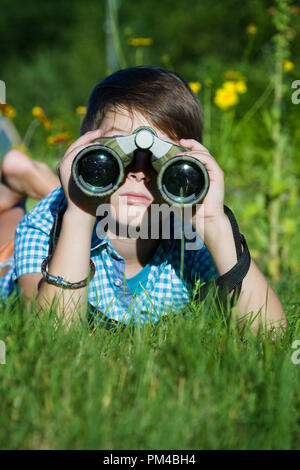 Junge junge Forscher erkunden mit Fernglas Umgebung im grünen Garten Stockfoto