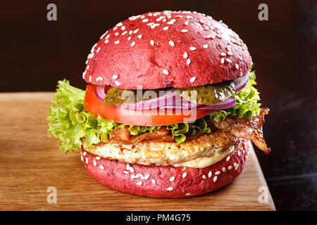 Red Burger mit Schnitzel, Speck und Gemüse, bestreut mit Sesam auf einer Tafel. Horizontale Foto mit freien Bereich für Text oder Design. Stockfoto