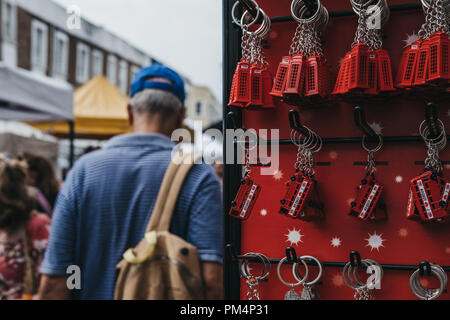 London, UK, 21. Juli 2018: Touristen zu Fuß vorbei an einem Stand mit Souvenir key chain auf Verkauf an Portobello Market, London, einer der beliebtesten Touris Stockfoto