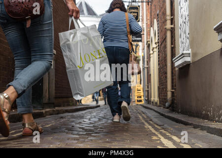 Niedrigen Winkel, Boden aus Sicht der weiblichen Käufer mit Tragetaschen hinunter eine schmale Straße in Windsor, UK. Stockfoto