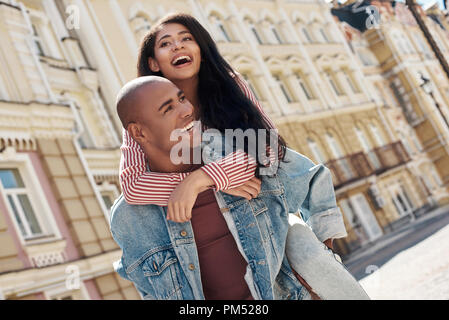 Romantische Beziehung. Junge diverse Paar gehen auf die Straße der Stadt Freund die Freundin auf der Rückseite Lachen glücklich Stockfoto