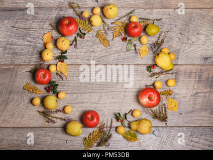 Kranz aus Herbst Blätter, Beeren, Äpfel und Nüsse auf Holz- Hintergrund. Herbst Konzept. Stockfoto