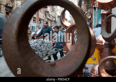 Ägypten, Kairo 2014. Khan al-Khalilli, alten islamischen Bereich. Junge treibt einen Wagen beladen mit Wasserpfeifen durch geschlagen copperwork gesehen. Stockfoto