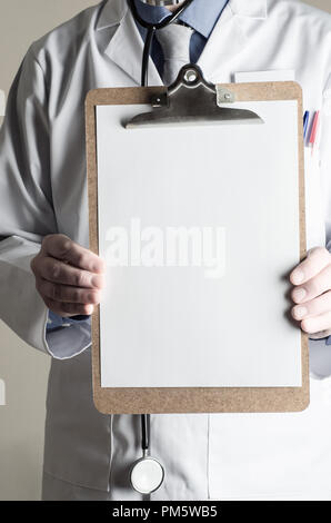 Männliches Modell gekleidet als Arzt. Nach vorne gedrückt halten, bis die Zwischenablage mit leeren Blatt Papier als ein Zeichen für Kopie Platz für eine Nachricht. Stockfoto