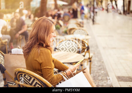 Shopper Frau Hand mit einem Smartphone Einkaufen und Tragetaschen Stockfoto