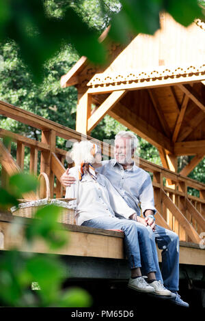 Schönes Foto von fröhlichen Rentner sitzen und Umarmen auf der Brücke Stockfoto