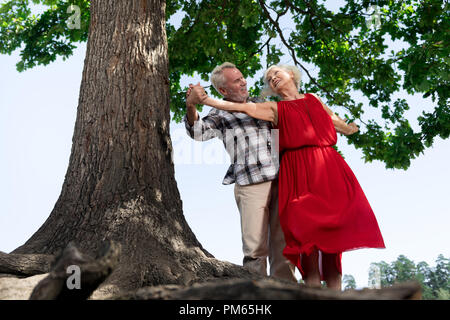 Adorable senior Paar tanzen durch den Baum und lächelnd Stockfoto