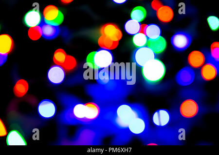 Unscharfer Hintergrund mit bunten bokeh Lichter auf dunklem Lila und Blau Hintergrund/verschwommen Weihnachtsbeleuchtung Stockfoto