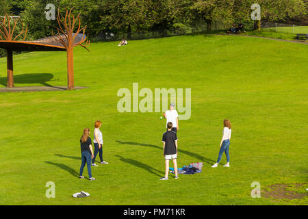 Eine Gruppe von fünf jungen Menschen spielen fangen mit einem kleinen Ball in den offenen Raum der Glebe, Bowness-on-Windermere, Cumbria. Stockfoto