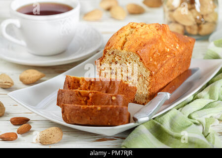 In Scheiben geschnitten pound Kuchen mit Mandeln auf dem Schneidebrett. Hausgemachte Kuchen mit Nüssen und Honig. Delikatesse Snack für Tee. Selektiver Fokus Stockfoto