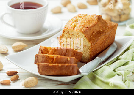 In Scheiben geschnitten pound Kuchen mit Mandeln auf dem Schneidebrett. Hausgemachte Kuchen mit Nüssen und Honig. Delikatesse Snack für Tee. Selektiver Fokus Stockfoto