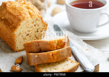 In Scheiben geschnitten pound Kuchen mit Mandeln auf dem Schneidebrett. Hausgemachte Kuchen mit Nüssen und Honig. Delikatesse Snack für Tee. Selektiver Fokus Stockfoto