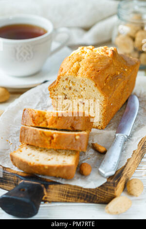In Scheiben geschnitten pound Kuchen mit Mandeln auf dem Schneidebrett. Hausgemachte Kuchen mit Nüssen und Honig. Delikatesse Snack für Tee. Selektiver Fokus Stockfoto