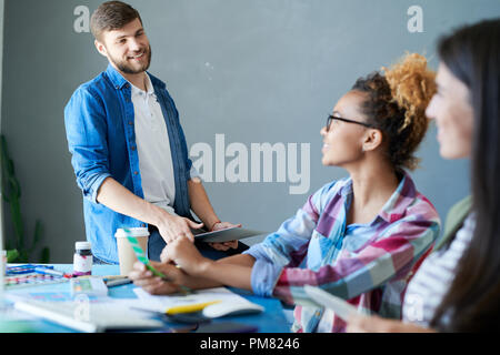 Porträt der lächelnde junge Unternehmer diskutieren kreatives Projekt mit Kollegen am Schreibtisch im Büro sitzen, Platz kopieren Stockfoto