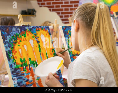 Junge Frau mit langen blonden Haaren Zeichnung auf einer Leinwand während der Masterclass in der Art Studio Stockfoto