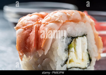 Sushi Rollen frische Garnelen Reis und Philadelphia Käse asiatische Lebensmittel auf dunklem Hintergrund mit eingelegten fermentiert Ingwer Meerrettich Wasabi in Soße Boot Stockfoto