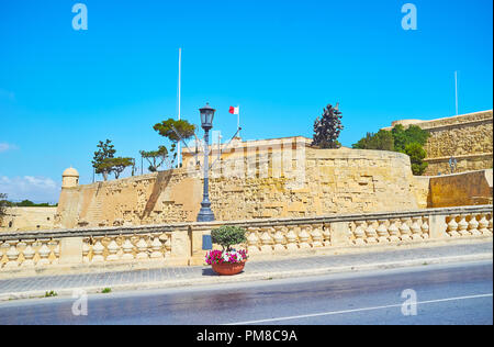 Die massive Wand von St James Bastion hinter dem Stein Handlauf, entlang der Girolamo Cassar Road, Valletta, Malta. Stockfoto