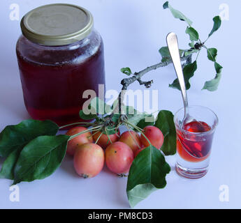 Wilde Äpfel mit lebendigen Farben auf einem Zweig und hausgemachte Marmelade auf weißem Hintergrund Stockfoto