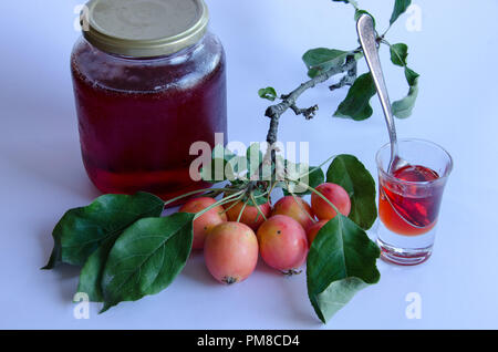 Wilde Äpfel mit lebendigen Farben auf einem Zweig und hausgemachte Marmelade auf weißem Hintergrund Stockfoto