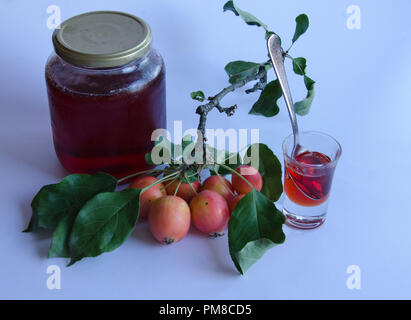 Wilde Äpfel mit lebendigen Farben auf einem Zweig und hausgemachte Marmelade auf weißem Hintergrund Stockfoto