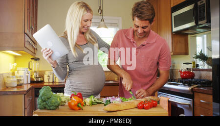 Süße schwangere Paare Kochen in der Küche Stockfoto