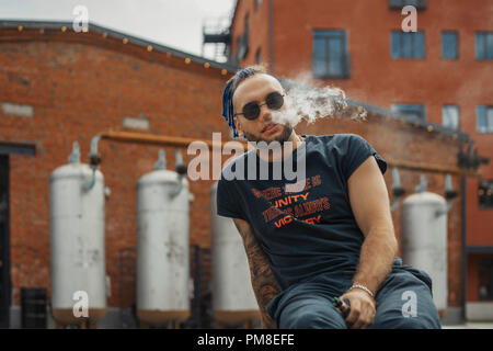Porträt der jungen vaping Mann mit Dreadlocks. Dampf Konzept. Vaping e-Zigarette Stockfoto