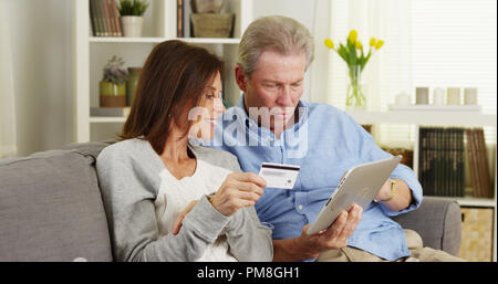 Senior Paar, einen Kauf auf Tablet aufgeregt Stockfoto