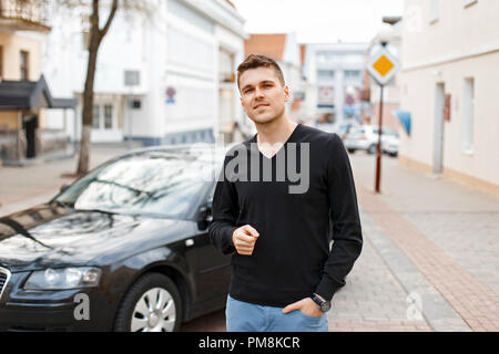 Hübscher junger Geschäftsmann Mann in der Nähe von einem schwarzen Auto auf der Straße Stockfoto