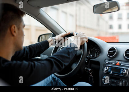 Junge männliche Fahrer sitzt im Auto und halten das Rad Stockfoto