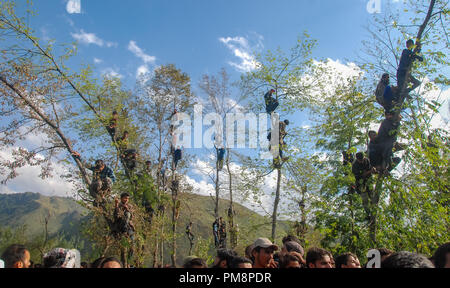 Kaschmir Dorfbewohner gesehen Beobachten von Baumkronen der Trauerzug von militanten Commander Gulzar Ahmed Paddar an seinem Heimatdorf Adijan Kulgam einige 65 km von Srinagar. Indische Truppen getötet 5 Kämpfer und ein Zivilist in eine Schießerei und Auseinandersetzungen im Süden von Kaschmir Kulgam Bezirk am Samstag. Stockfoto