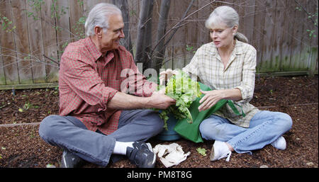 Reifes Paar sitzt und spricht im Garten Stockfoto