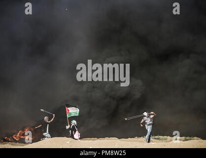 Ein palästinensischer Mann mit einer Schleuder Steine gegen israelische Truppen während der Auseinandersetzungen zu werfen. Auseinandersetzungen zwischen palästinensischen Demonstranten und israelischen Kräfte während eines Protestes entlang der israelischen Zaun östlich von Gaza-stadt. Stockfoto