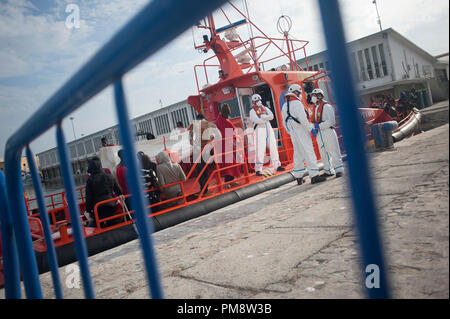 Migranten gesehen, stehend auf einem Rettungsboot durch Helfer überwacht wird nach gerettet werden. Mitglieder der Spanischen Sicherheit auf See gerettet Insgesamt 64 Migranten an Bord eines Beiboot von Alboran See, und brachte sie nach Malaga Hafen, wo sie durch das Spanische Rote Kreuz unterstützt wurden. Stockfoto