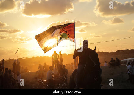 Ein palästinensischer Mann gesehen ein Pferd Reiten und winkte eine palästinensische Flagge während der Auseinandersetzungen. Auseinandersetzungen zwischen palästinensischen Demonstranten und israelischen Kräfte während eines Protestes entlang der israelischen Zaun östlich von Gaza-stadt. Stockfoto