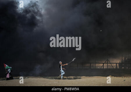 Ein palästinensischer Mann mit einer Schleuder Steine gegen israelische Truppen während der Auseinandersetzungen zu werfen. Auseinandersetzungen zwischen palästinensischen Demonstranten und israelischen Kräfte während eines Protestes entlang der israelischen Zaun östlich von Gaza-stadt. Stockfoto