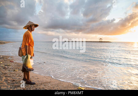 Bali, Indonesien, September 11th, 2016: alte Fischer am Strand mit seinem Fisch Netze Stockfoto