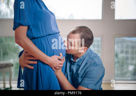 Mann küssen schwanger Frau Bauch zärtlich. Im Vorgriff auf das Kind, Schwangere und Familie Konzept Stockfoto