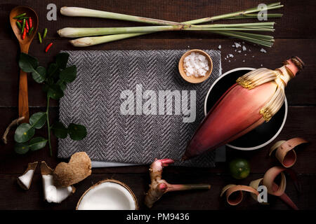 Thai Food Zutaten zum Kochen mit Bananen Blüte, Kokos, Zitronengras, Chili, Salz, Zitrone, Limette Blatt, Löffel aus Holz und Stoff auf Holzbrett hinterg Stockfoto