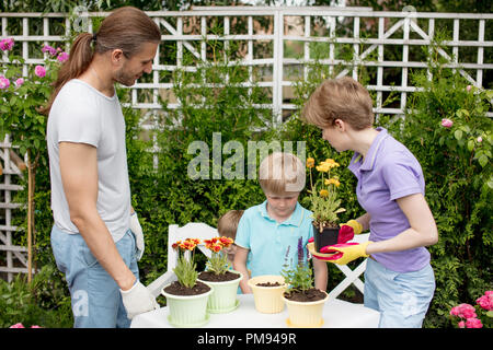 Junge Mutter Gartenarbeit in den vorderen oder hinteren Hof mit ihren zwei süße kleine Kinder Stockfoto