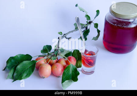 Wilde Äpfel mit lebendigen Farben auf einem Zweig und hausgemachte Marmelade auf weißem Hintergrund Stockfoto