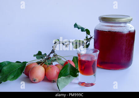 Wilde Äpfel mit lebendigen Farben auf einem Zweig und hausgemachte Marmelade auf weißem Hintergrund Stockfoto