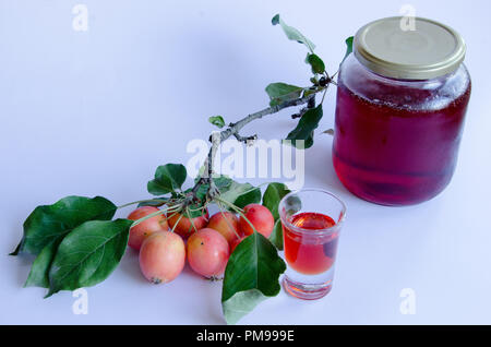 Wilde Äpfel mit lebendigen Farben auf einem Zweig und hausgemachte Marmelade auf weißem Hintergrund Stockfoto