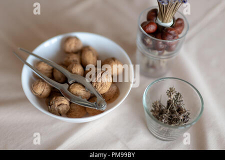Nussknacker und Walnüsse in eine Schüssel auf einen Tisch mit Tischdecke bedeckt. Snack auf dem Küchentisch. Hellen Hintergrund. Stockfoto