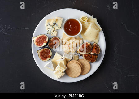 Käseplatte mit Früchten und Keksen auf dunklem Hintergrund Stockfoto