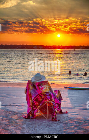 Strandurlauber und Schwimmer genießen Sie den Sonnenuntergang über der Bank. Wrightsville Beach, NC Stockfoto