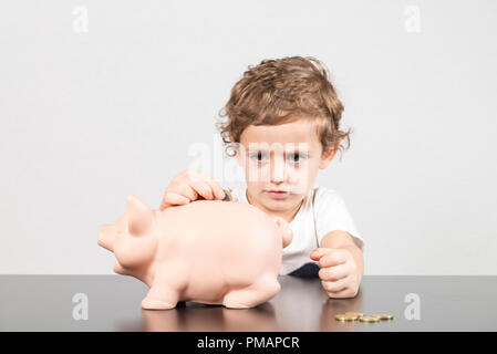 Kind Münzen einfügen in ein Sparschwein Stockfoto