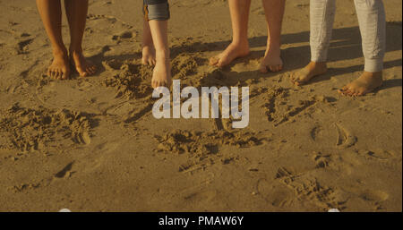 Freunde mit ihren Füßen am Strand zu schreiben Stockfoto